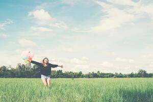 Jeune femme tenant un ballon sur une prairie verte en cours d'exécution et profitant de l'air frais photo