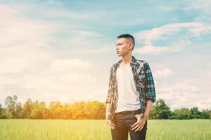 jeune bel homme debout dans un champ vert photo