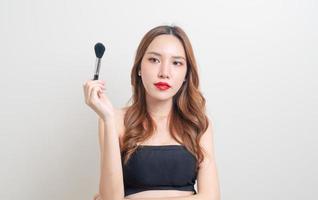 Portrait belle femme asiatique avec pinceau de maquillage sur fond blanc photo