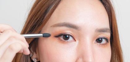 Portrait belle femme asiatique avec pinceau pour les yeux de maquillage sur fond blanc photo