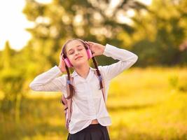 belle petite fille écoutant de la musique sur des écouteurs dans le parc d'automne photo