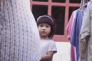 une petite fille accompagne sa mère en train de sécher des vêtements. photo