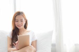 jeune femme asiatique tenant et lisant une tablette numérique. photo