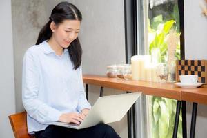jeune femme asiatique travaillant en ligne sur un ordinateur portable. photo