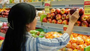 portrait de une magnifique asiatique ou indonésien femme achat fruit arrangé sur fruit grille dans une supermarché photo
