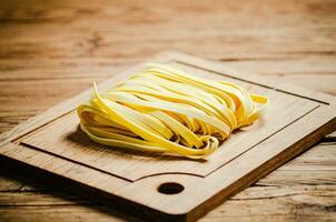 fait maison Pâtes tagliatelles. sur en bois tableau. photo