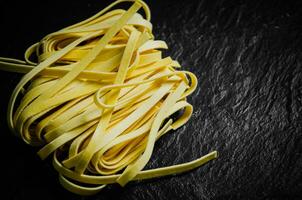 fait maison Pâtes tagliatelles. sur noir tableau. photo