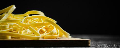 fait maison Pâtes tagliatelles. sur noir tableau. photo