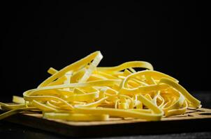 fait maison Pâtes tagliatelles. sur noir tableau. photo