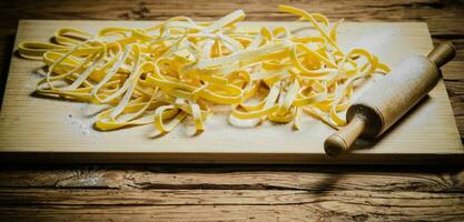 fait maison Pâtes tagliatelles. sur en bois tableau. photo