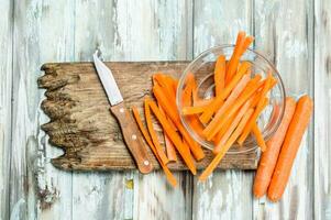 tranché carottes sur une Coupe planche avec une couteau. photo