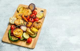 grillé des légumes avec épices et herbes sur une Coupe planche. photo