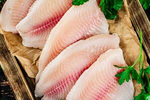 poisson filet avec persil sur une en bois plateau. photo