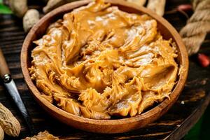 une assiette de cacahuète beurre sur une en bois Contexte. photo