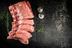 pièces de brut porc sur une pierre planche avec Romarin et épices. photo