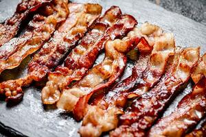 bandes de frit Bacon sur une noir Contexte. photo