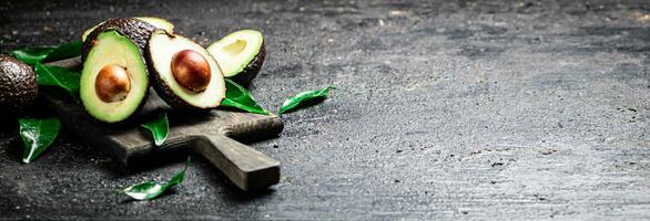 Frais Avocat avec feuillage sur une Coupe planche. photo