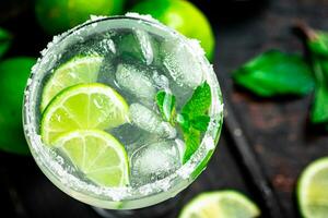 Margarita sur une Coupe planche avec pièces de citron vert et menthe feuilles. photo