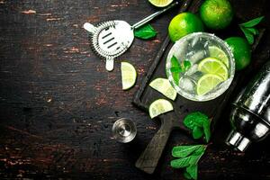 Margarita sur une Coupe planche avec pièces de citron vert et menthe feuilles. photo