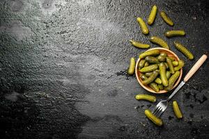 en bois assiette avec cornichons. sur une noir Contexte. photo