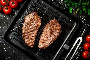 grillé steak dans une friture la poêle avec tomates et épices. photo