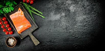 salé Saumon avec légumes verts et tomates sur une Coupe planche. photo
