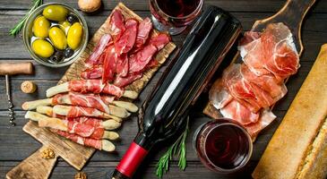 antipasto arrière-plan.divers Viande apéritif avec Olives, jamon et rouge du vin. photo