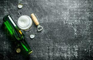 Bière dans une verre et une verre bouteille avec ouvreur. photo