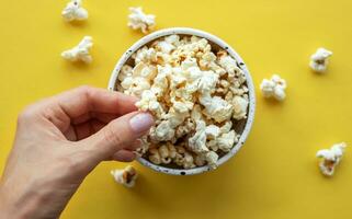 une femme main prend pop corn de une Coupe. photo