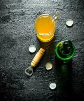 Bière dans une verre et un ouvert verre bouteille avec ouvreur. photo