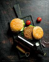 des hamburgers et Bière dans une bouteille sur le Coupe planche. photo