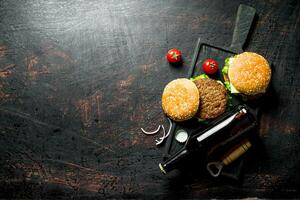 des hamburgers et Bière dans une bouteille sur le Coupe planche. photo