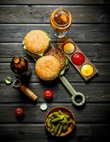 des hamburgers avec bière, cornichons et sauces. photo