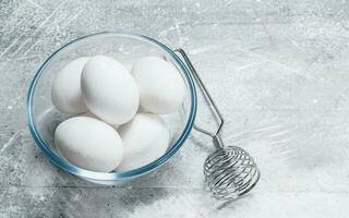 des œufs dans une verre bol avec une fouet. photo
