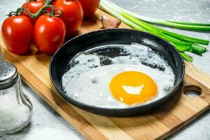 frit Oeuf dans une la poêle avec tomates et vert oignons. photo