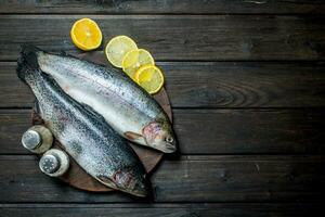 Saumon brut poisson sur une Coupe planche avec citron. photo