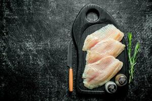 poisson filet sur une Coupe planche avec une couteau, épices et Romarin. photo