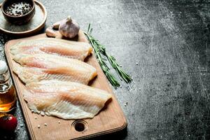 poisson filet sur une Coupe planche avec Romarin, Ail et épices dans une bol. photo