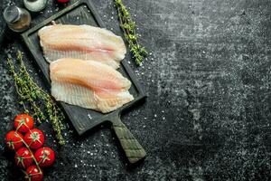 poisson filet sur une Coupe planche avec tomates et thym. photo