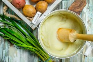 en purée patates dans une la poêle avec vert oignons. photo