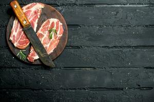 brut porc steak avec un vieux couteau sur une Coupe planche. photo