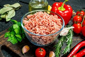 brut haché Viande dans une bol avec des légumes et herbes. photo