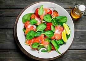 poisson salade. salade avec tranches de saumon, tomates et épinard avec citron vert jus. photo