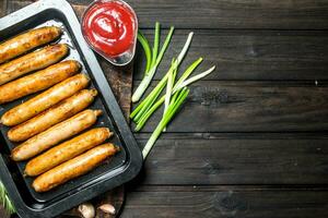 frit saucisses avec sauce et vert oignons. photo