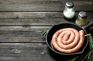 brut saucisses dans une la poêle avec herbes et assaisonnements. photo