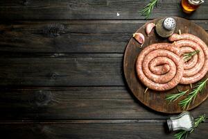 brut saucisses avec herbes sur une en bois planche. photo