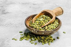 citrouille des graines dans bol avec en bois scoop. photo