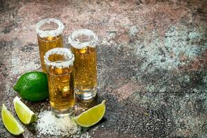 Tequila dans une coup verre de sel et citron vert tranches. photo