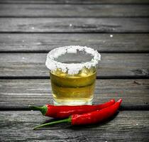 Tequila dans une verre de sel et chaud poivre gousses. photo