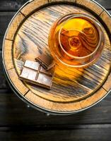 Cognac dans une verre avec Chocolat sur une baril. photo